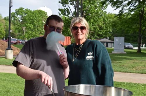 DON Services Outdoor Event Two people enjoying an outdoor event with cotton candy and a large cooking pot.