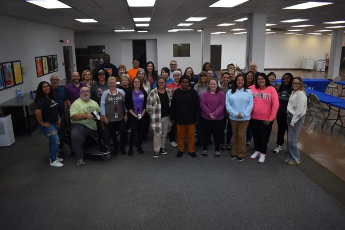 Group photo of DON Services team members in a modern office setting.